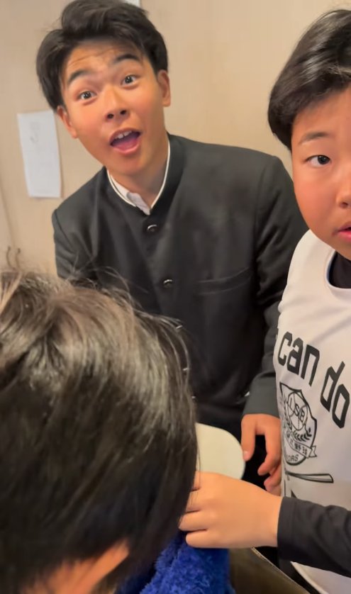 驚いた表情でカメラを見つめる制服を着た子供