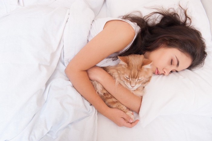 猫を抱きしめながら眠る女性