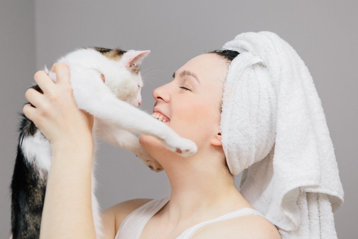 頭にタオルを巻いて猫を抱く女性