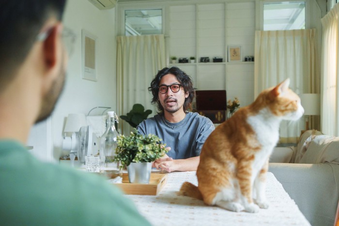 話している2人とテーブルの上の猫