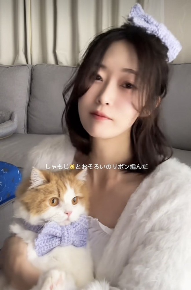 リボンを付けてママに抱っこされるミヌエット