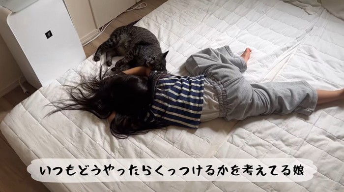 倒れる真似をしている女の子と猫