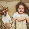 女性は犬と一緒に眠…
