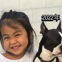 笑顔で写真に撮られる女の子と、視線を逸らす犬