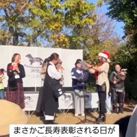 賞状を読み上げる女性の前に立つ飼い主と犬