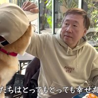 お父さんに帽子を被せてもらう犬