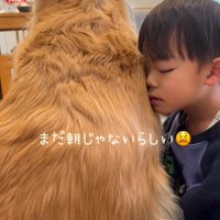 目を閉じたまま犬にもたれかかる男の子