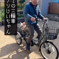 電動式三輪車に跨がってカメラに視線を送る年配男性