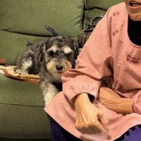 おばあちゃんの隣に座る犬
