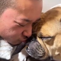 顔をくっつけて目を閉じている犬と男性