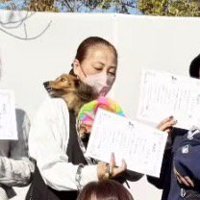 犬を抱っこしながら表彰状を持って記念撮影する飼い主