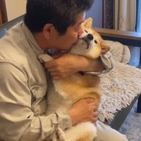 犬の頬に顔を寄せる男性