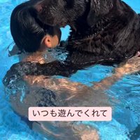 プールで子どもと犬が抱き合っている