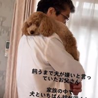 飼い主に抱かれている小型犬