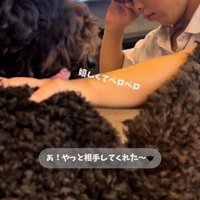 目をこすりながら犬をなでる男の子
