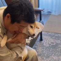 抱きしめている犬を床に降ろそうとする男性