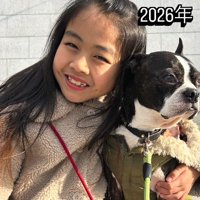 笑顔で写真に撮られる4年後の女の子と、カメラから視線を逸らす犬