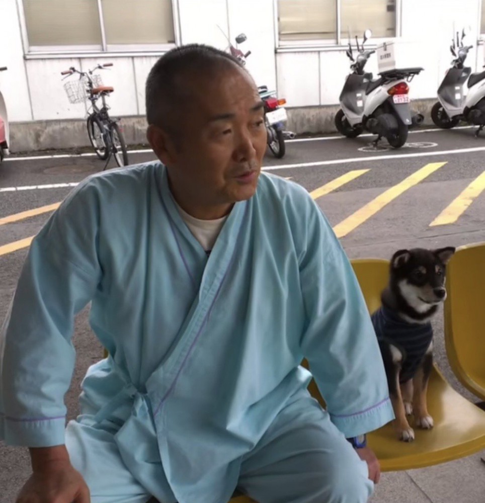 入院中のおじいちゃんと並んで座る子犬