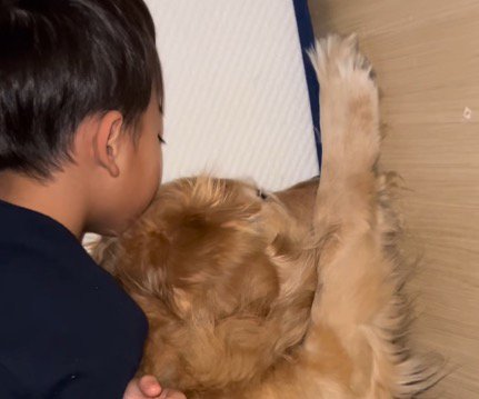 犬の頭に顔をくっつけて眠る男の子