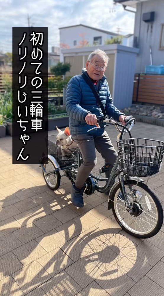 電動式三輪車に跨がってカメラに視線を送る年配男性