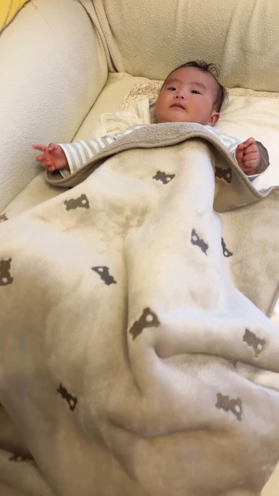 ブランケットの中で手足を動かす赤ちゃん