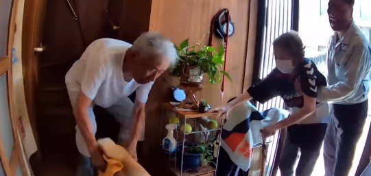 老年男性の腕をすり抜けて老年女性に駆け寄る犬