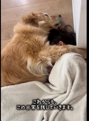 毛布に包まれた子どもと寄り添って眠る犬