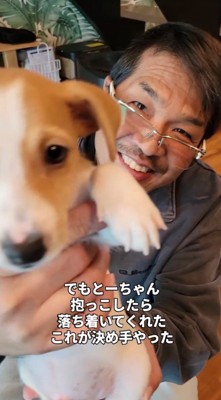 子犬を抱っこして笑顔を見せる男性