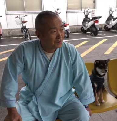 入院中のおじいちゃんと並んで座る子犬