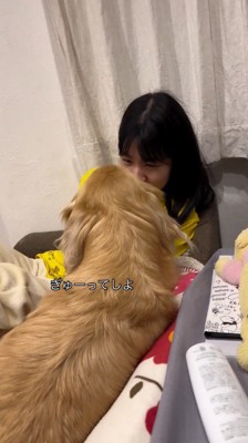 女の子に顔を近づけて甘える犬