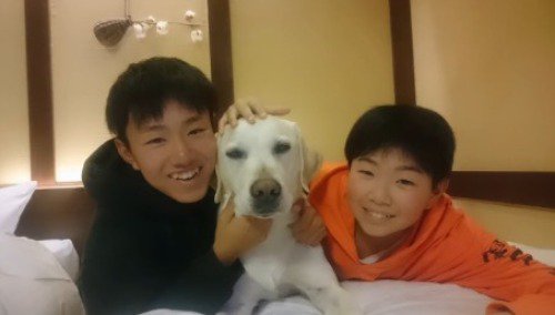 横に並んで笑顔の犬と2人の男の子