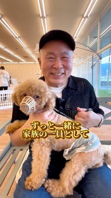 犬を抱っこしながらスタッフと話をする犬