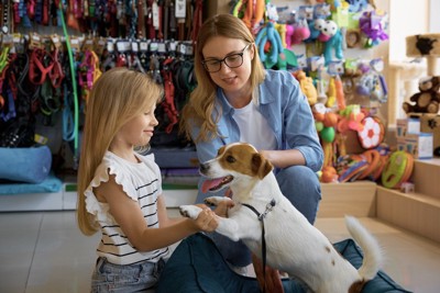 ペットショップで商品を選ぶ犬と親子