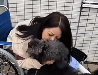 女性にギュッと抱きしめられる犬
