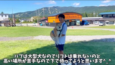 男性に抱えられる柴犬