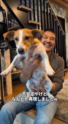 犬を抱き上げる男性