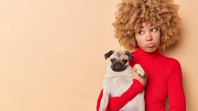犬を抱っこして不満そうな女性