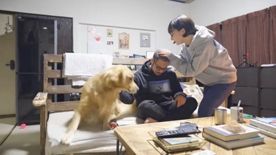 女性に頭をなでられる男性と犬