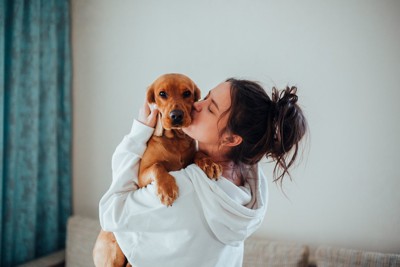 女性にキスをされている犬