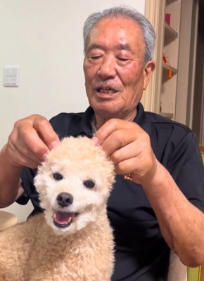 トイプードルの耳で遊ぶ男性と笑顔のトイプードル