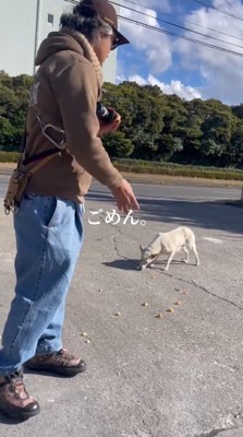 犬のそばにおやつを撒く男性