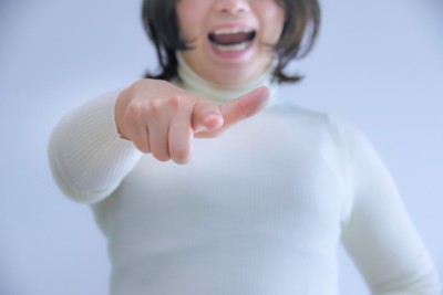白い服を着た、指をさして怒る