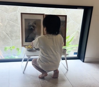 しゃがんで遺影を見つめる子ども