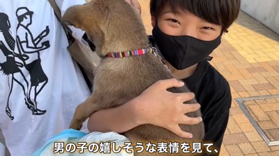 男の子に抱っこされる子犬の後姿