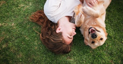 芝生の上で寝転がる犬と女の子