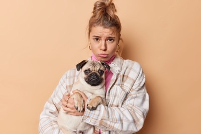 犬を抱っこして不満そうな女性