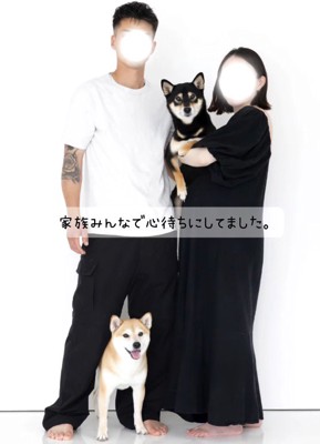 女性に抱っこされる黒い犬と、男性の足の間に座る茶色い犬