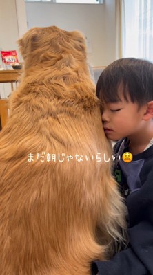 目を閉じたまま犬にもたれかかる男の子