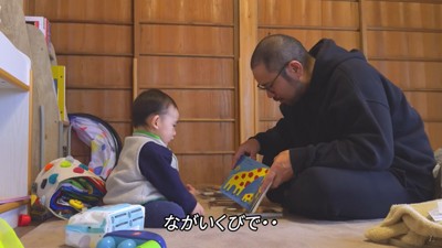 子どもに絵本を見せる男性