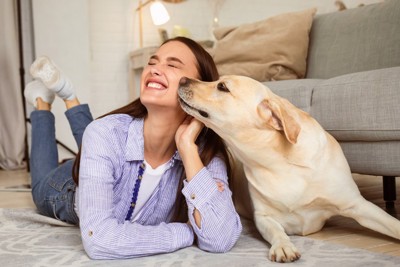人の顔に口元を寄せる犬